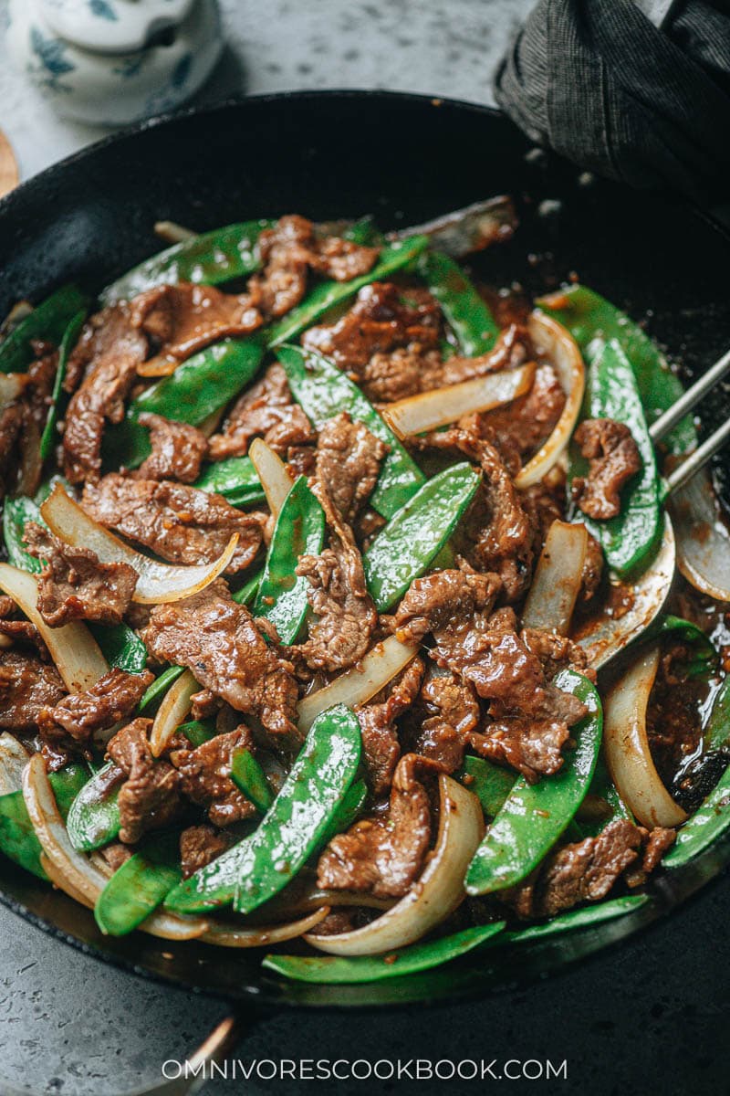Stir fried beef, snow peas and onion in a pan